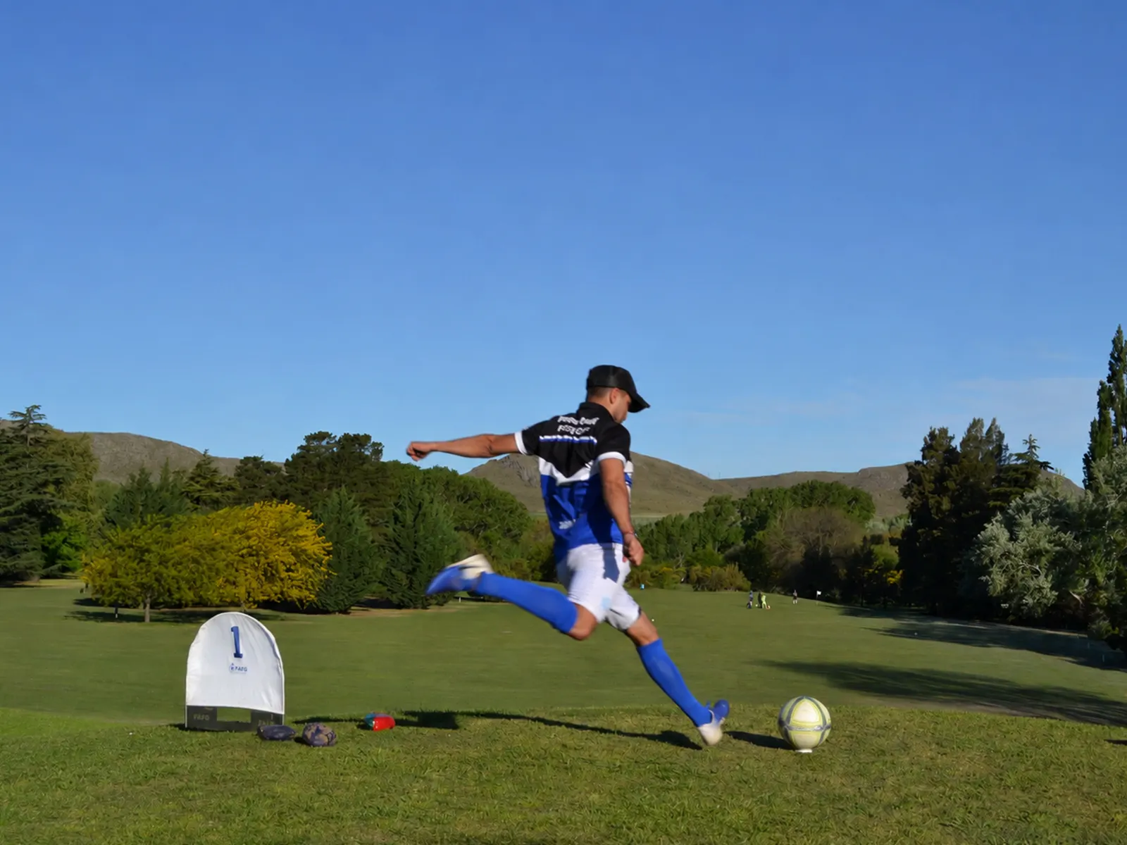 Jugador de footgolf pateando una pelota en una cancha al aire libre en Tandil